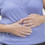 mature woman with leaky gut holding her stomach